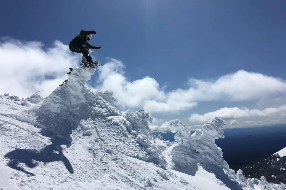 An exterior shot featuring a snowboarder carving down a snowy peak with dramatic clouds and mountain scenery all around. The outdoors is the central focus, emphasizing adventure and exploration.