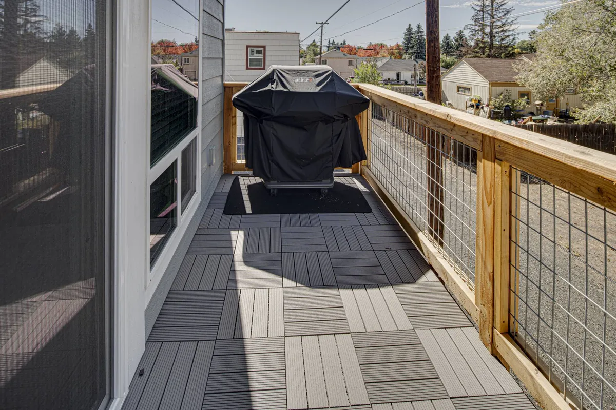 A close-up look at the deck, featuring a grill, deck flooring, and sturdy railing. The setup is casual and inviting, suggesting opportunities for barbecuing, reading, or simply soaking up the outdoor ambiance. The scene conveys comfort and versatility.